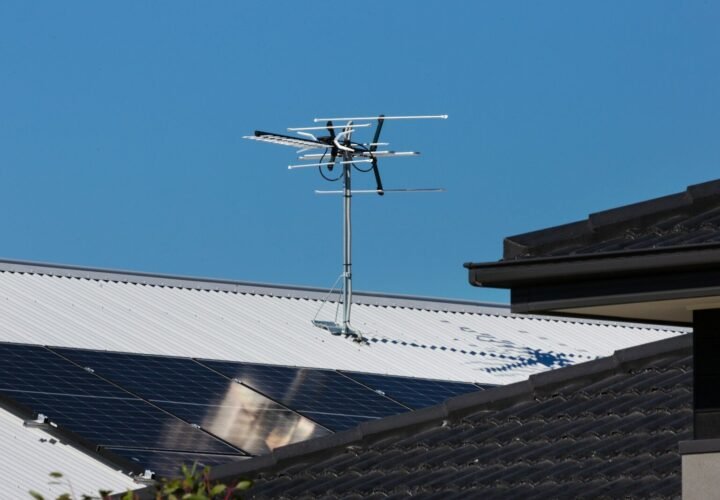 A television antenna stands tall against a clear blue sky